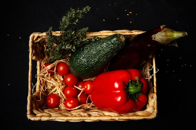 Cesta con verduras en una habitación oscura Vista superior de los champiñones de tomate berenjena y pimienta