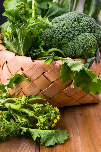 cesta con verduras verdes frescas sobre un fondo de madera. Aguacates, brócoli, cime di rapa otros verdes. Espacio libre para texto. Copia espacio