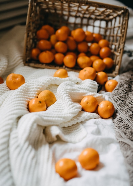 Cesta volcada llena de naranjas sobre mantas en la cama.