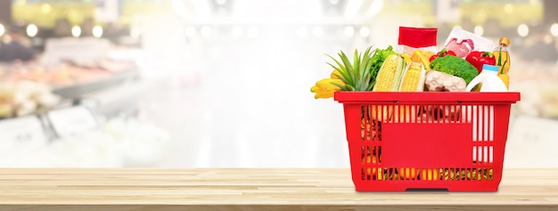 Cesto de compras cheio de comida e mantimentos na mesa no supermercado