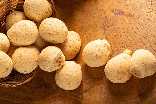 Cesto de pão de queijo com pão de queijo arranjado em madeira rústica fundo escuro foco seletivo