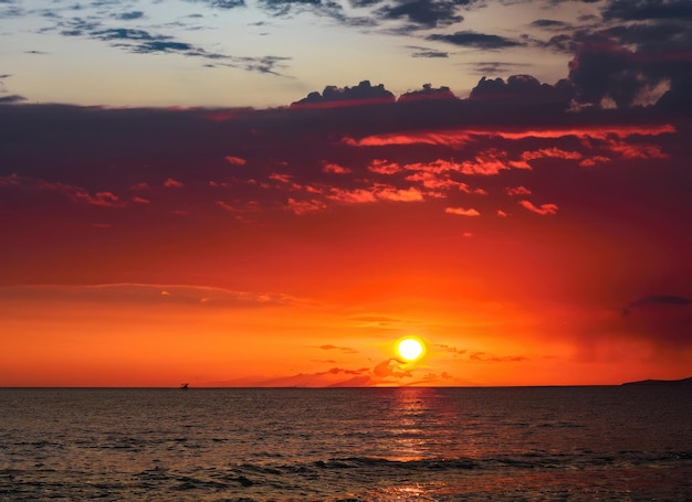 Céu ao pôr-do-sol com reflexos na luz do sol na água e nuvens laranjas coloridas