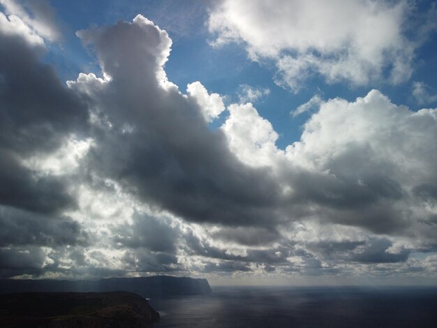 Céu arejado abstrato com nuvens gordas em movimento sobre as ondas pequenas do oceano marinho na superfície da água clara