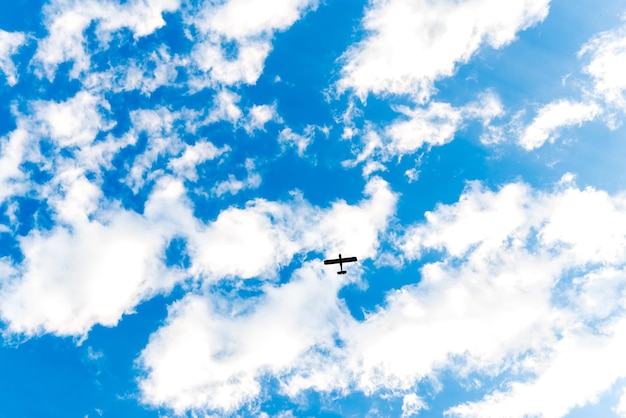 Céu azul com a silhueta de um avião voando entre as nuvens