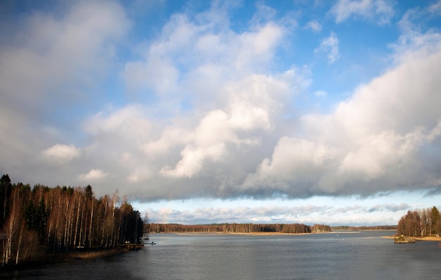 Céu azul com nuvens e reflexo do sol na água com lugar para o seu texto incrível lago de nuvens na Finlândia e no outono do céu