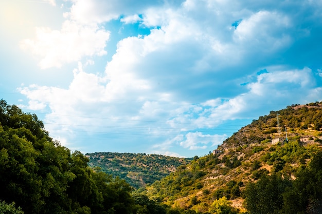 Céu azul com nuvens sobre a montanha com floresta verde em um dia ensolarado