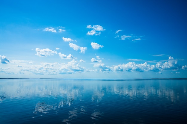 Céu azul de nuvens brancas fofas acima de uma superfície do mar.