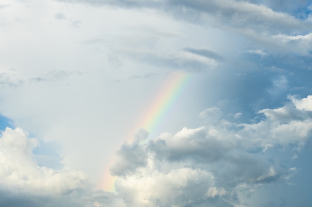 Céu azul e nuvem branca com arco-íris