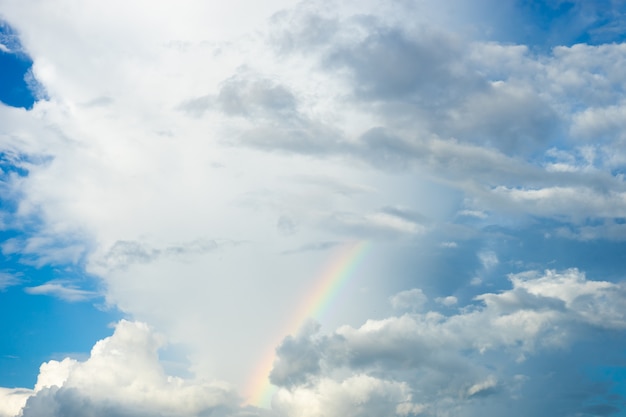 Céu azul e nuvem branca com arco-íris