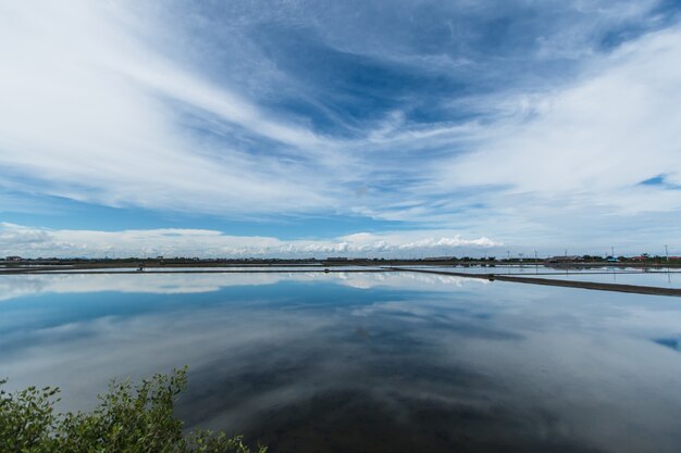 Céu azul e nuvens brancas, reflexões de água na agricultura de sal (Naklua), Phetchaburi Thailan