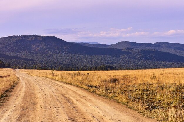 Céu azul Floresta verde Altas montanhas Estrada poeirenta