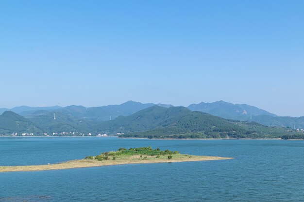 Céu azul, montanhas e árvores verdes cercam o lago