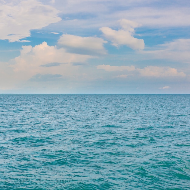 Céu azul nublado, deixando para o horizonte acima de uma superfície azul do mar