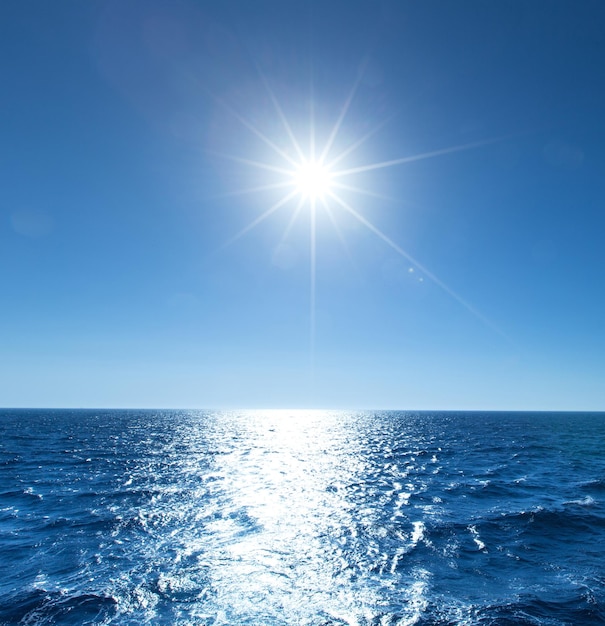 Céu azul sobre mar calmo com reflexo da luz do sol