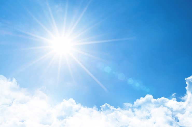 Foto céu claro, com sol brilhante e raios na atmosfera, abaixo estão nuvens macias e leves.