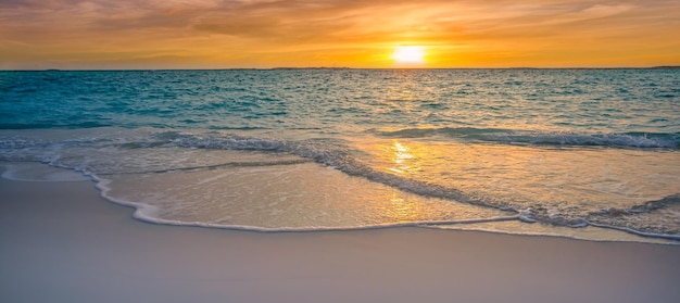 Céu de nuvens douradas, reflexo do sol na água e areia na praia. Conceito de férias românticas
