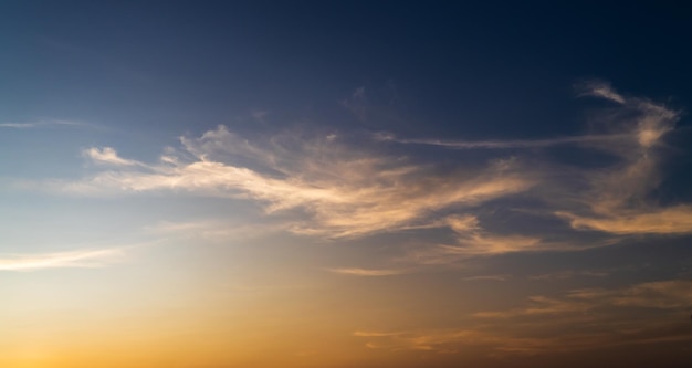 Céu do sol colorido à noite com nuvens de luz solar laranja em azul escuro