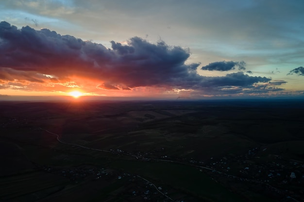 Céu do sol colorido brilhante com sol e nuvens vibrantes sobre a paisagem escura