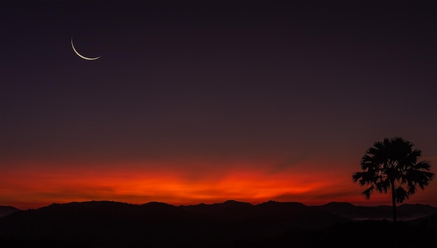 Foto céu do sol sobre montanhas de silhueta e árvore com lua crescente ao entardecer bem espaço livre para texto