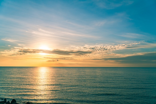 Céu do sol sobre o mar à noite com luz solar laranja colorida