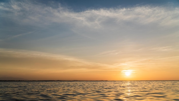 Céu do sol sobre o mar à noite com luz solar laranja