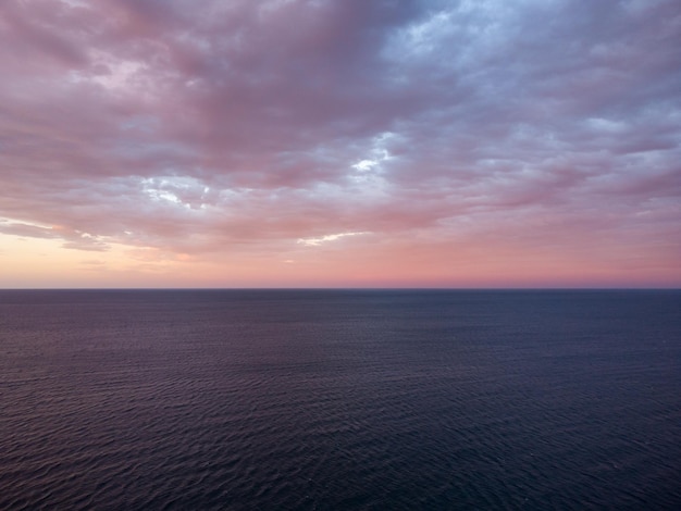 Céu do sol sobre o mar à noite com nuvens coloridas laranja