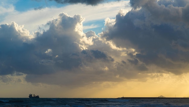 Céu escuro com raios de sol e um navio no mar