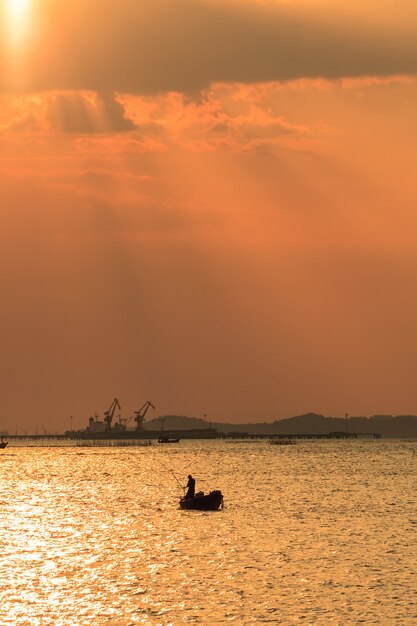 Foto céu laranja e fisher homem com fundo de navio de carga