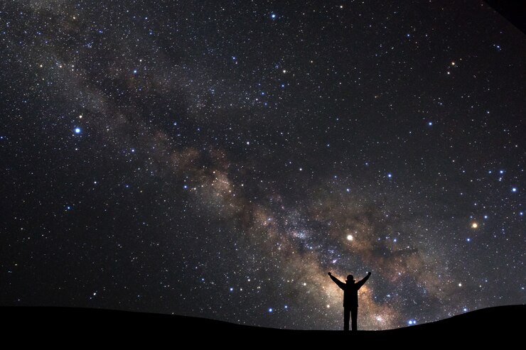 Foto céu noturno com estrelas e silhueta de um homem desportivo com braços erguidos