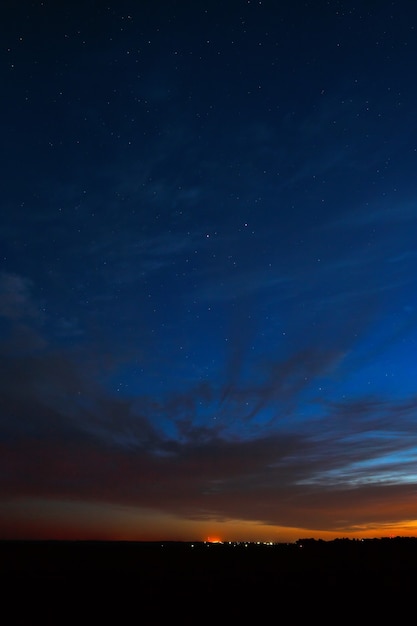 Céu noturno com estrelas. Um pôr do sol brilhante com nuvens. Espaço cósmico acima da superfície da Terra. Exposição longa.