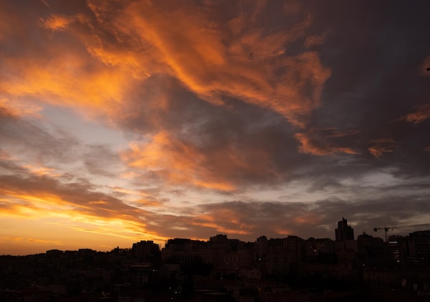 Céu nublado amarelo e pôr do sol ou nascer do sol. Céu dourado e silhueta escura da cidade.