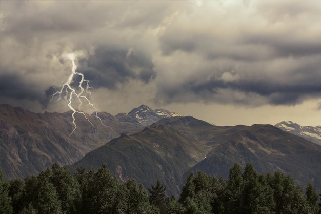 Céu nublado escuro com relâmpagos sobre belas árvores e montanhas Tempestade