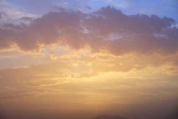 Céu vermelho brilhante dramático com nuvens cinzentas alaranjadas ao pôr do sol sobre uma paisagem de floresta de montanha escura na hora dourada