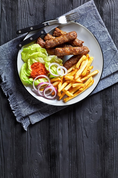 Cevapcici con papas fritas lechuga cebolla ajvar