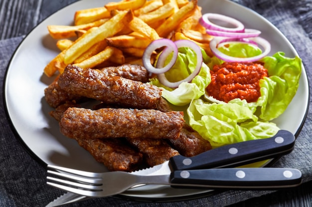 Cevapcici con papas fritas lechuga cebolla ajvar