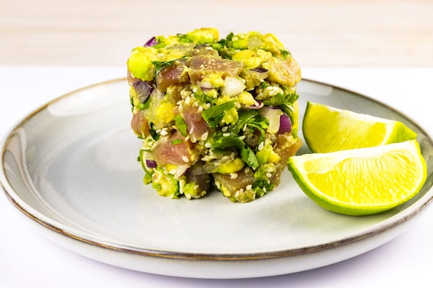 Ceviche de atum e abacate em prato cinza na mesa de madeira branca