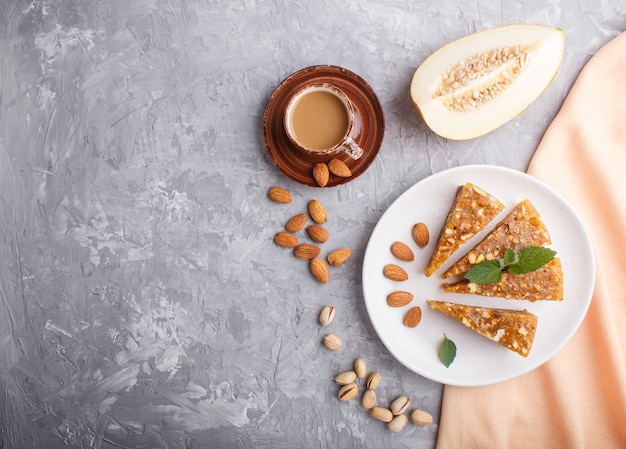 Cezerye tradicional turco de melón caramelizado, pistachos en plato blanco y una taza de café