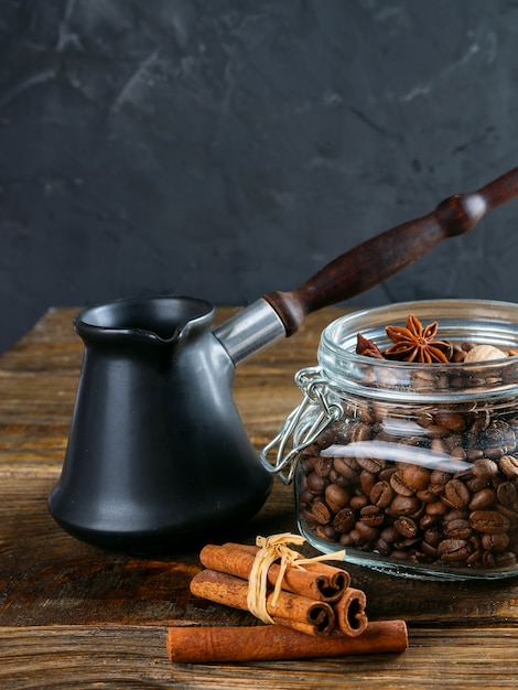 Cezve und geröstete Kaffeebohnen im Kasten auf einem rustikalen Tisch, Zimt und getrocknete Zitrone.