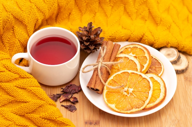 Chá aromático quente com paus de canela e fatias de laranjas secas. em uma mesa de madeira