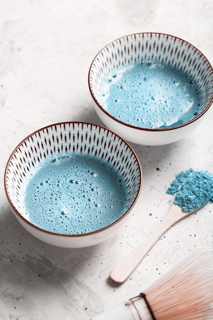 Chá azul matcha em uma tigelas e chasen na superfície de concreto