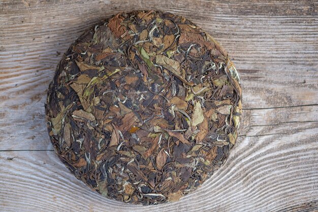 Chá branco chinês natural em forma de panqueca. chá redondo pressionado em um suporte de madeira