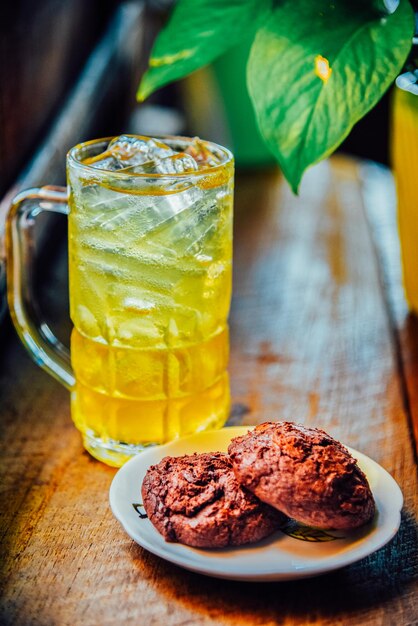 Foto chá chinês de crisântemo em copo alto e biscoitos de brownie em mesa de madeira chá de ervas de saúde