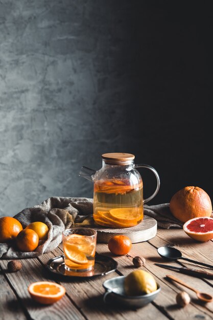 Chá cítrico em um bule transparente sobre uma mesa com toranja e sobre uma mesa de madeira. bebida saudável.