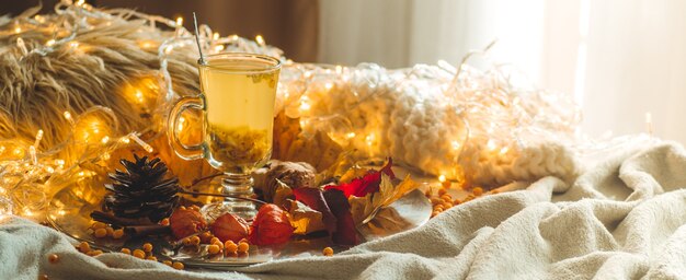 Chá com bagas de espinheiro e gengibre em livros antigos, mel, vela e folhas de outono. a atmosfera de conforto em casa. casa aconchegante e aconchegante.