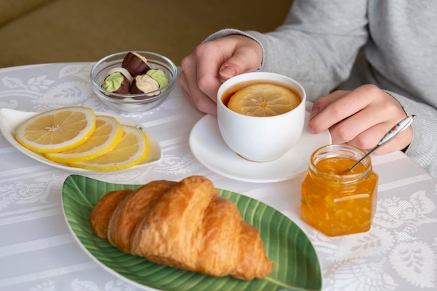 Chá com limão, geléia, croissant e chocolates em uma mesa branca