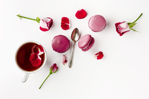 Chá da manhã na mesa branca com rosas e macarons