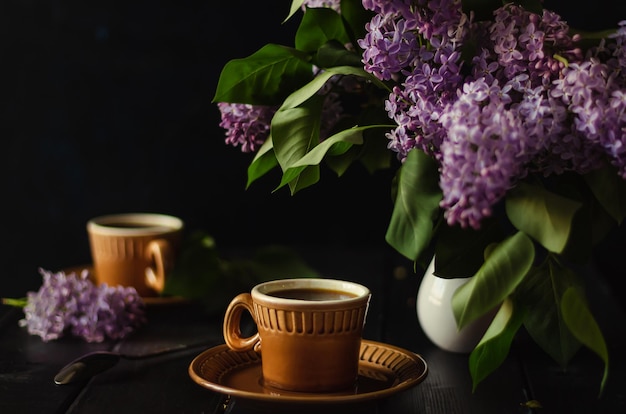 Chá da noite com um amigo em um ambiente aconchegante Canecas marrons em desfoque Foco suave de tecla escura em flores lilás