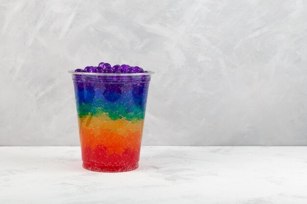 Chá de bolhas de arco-íris em copo de plástico descartável Coquetel refrescante de verão Bebida multicolorida Boba