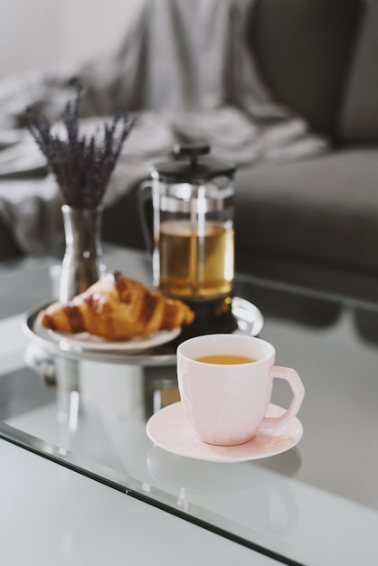 Chá de ervas e croissant fresco servidos em uma bandeja de metal café da manhã em uma mesa de centro
