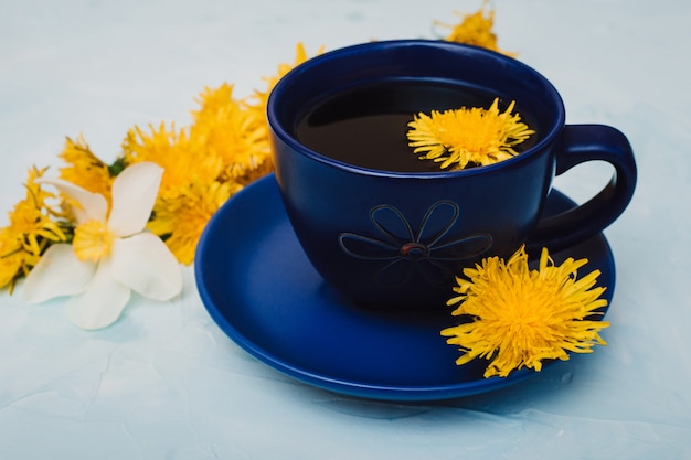 Foto chá de ervas em copo azul com flores-leão